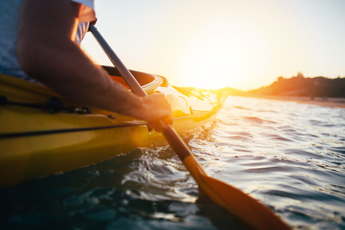 Kayak Close up of man holding kayak paddle at sunset